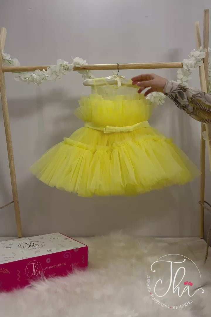 360° view of a yellow sleeveless tutu dress that has knee length fluffy multi layered skirt, belt, and yellow illusion collar