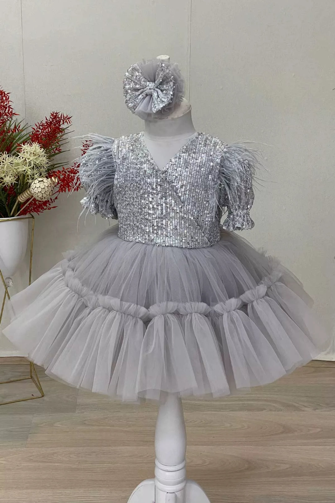 A gray girl dress that has sequins, half sleeve, feathers, V-neck, and puffy skirt