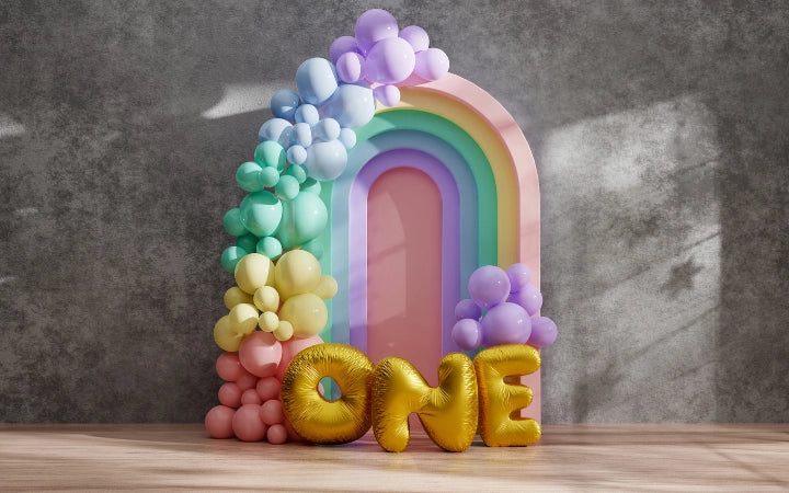 Pastel rainbow balloon arch with gold ONE balloons for a first birthday