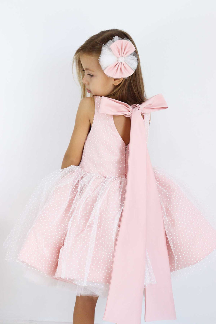 Back view of a pink sleeveless birthday dress that has snow foam, knee length fluffy skirt, bow, and satin top