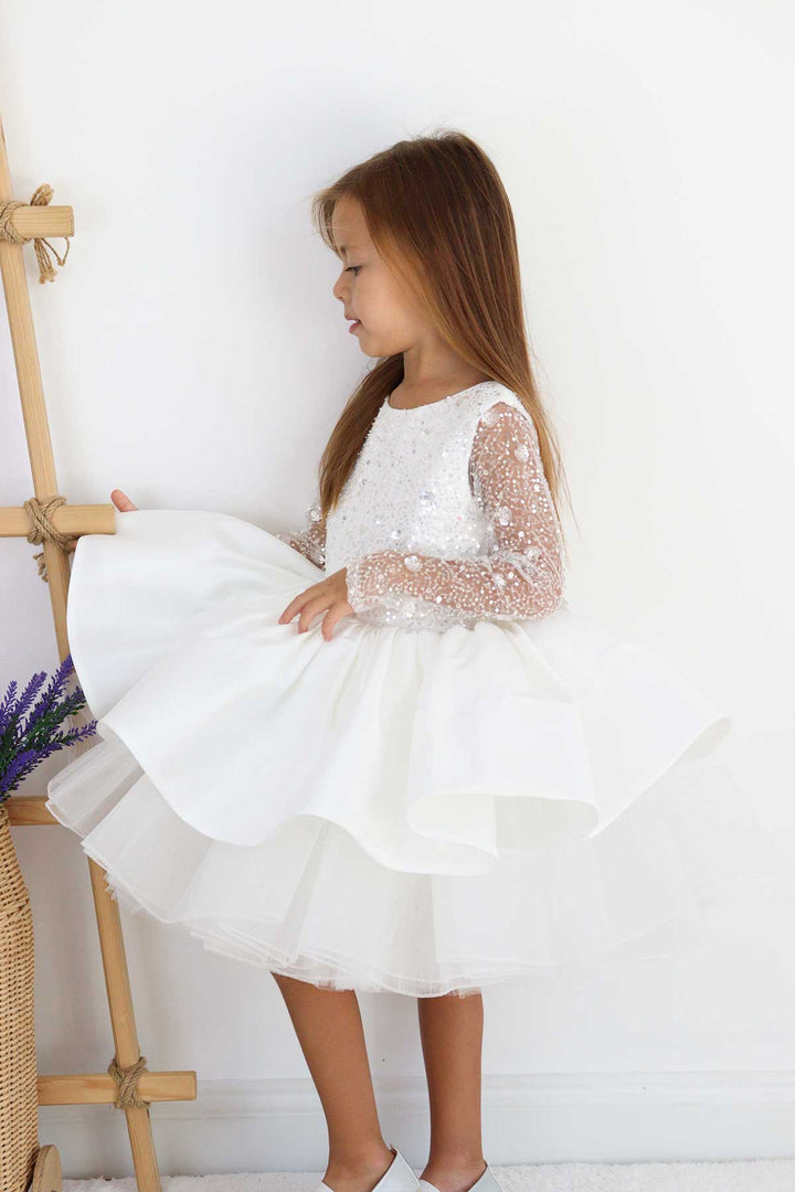 A white full sleeve bridesmaid dress that has white 3D sequins and knee length puffy skirt