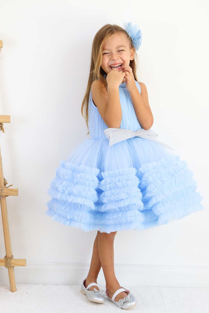 A blue sleeveless elegant dress that has judge collar, tulle top, shirred tulle knee length skirt, and shiny tulle bow