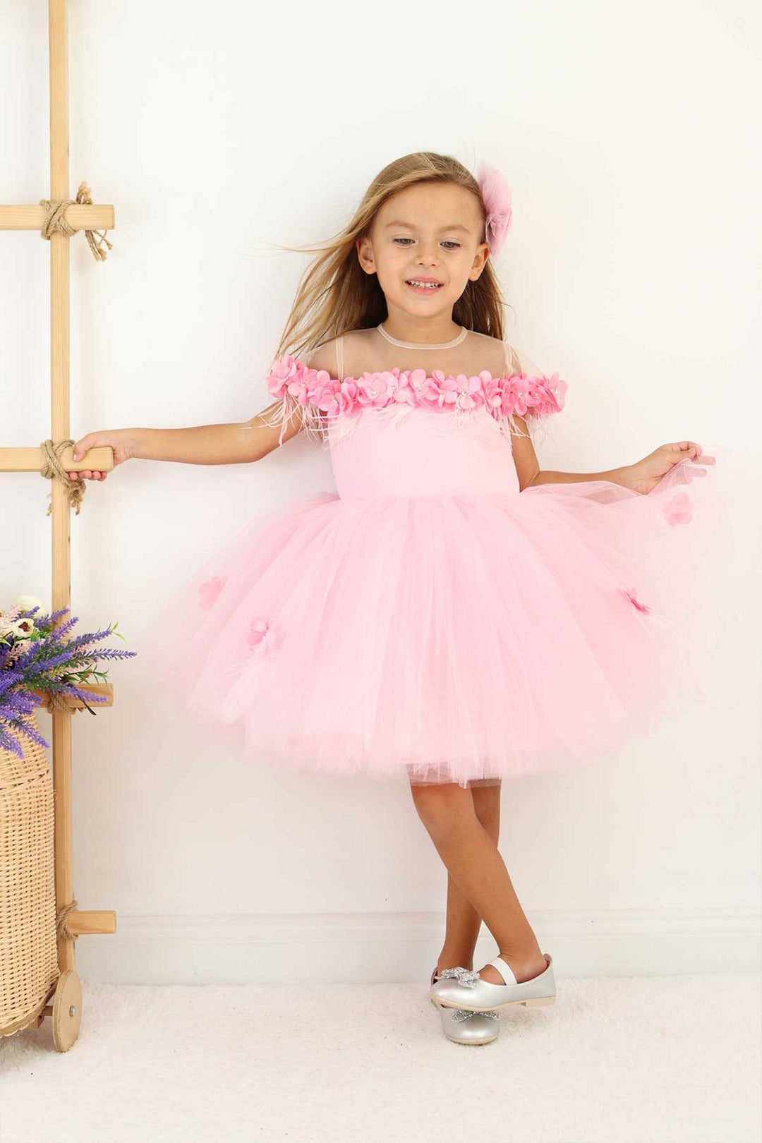 A pink sleeveless fairy dress that has 3D flowers with rhinestones, cap sleeve, feathers, illusion collar, satin top, and knee length skirt