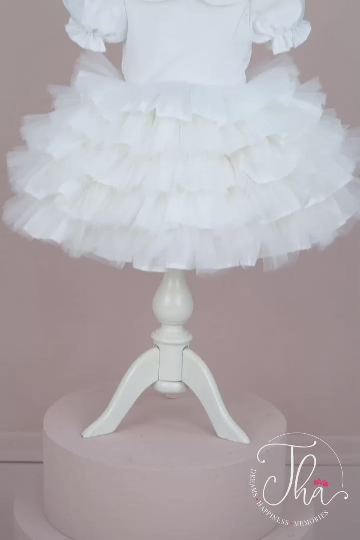 360° view of a baby girl dress that has satin top, puffy skirt, half sleeves, bow, and feathers on shoulders