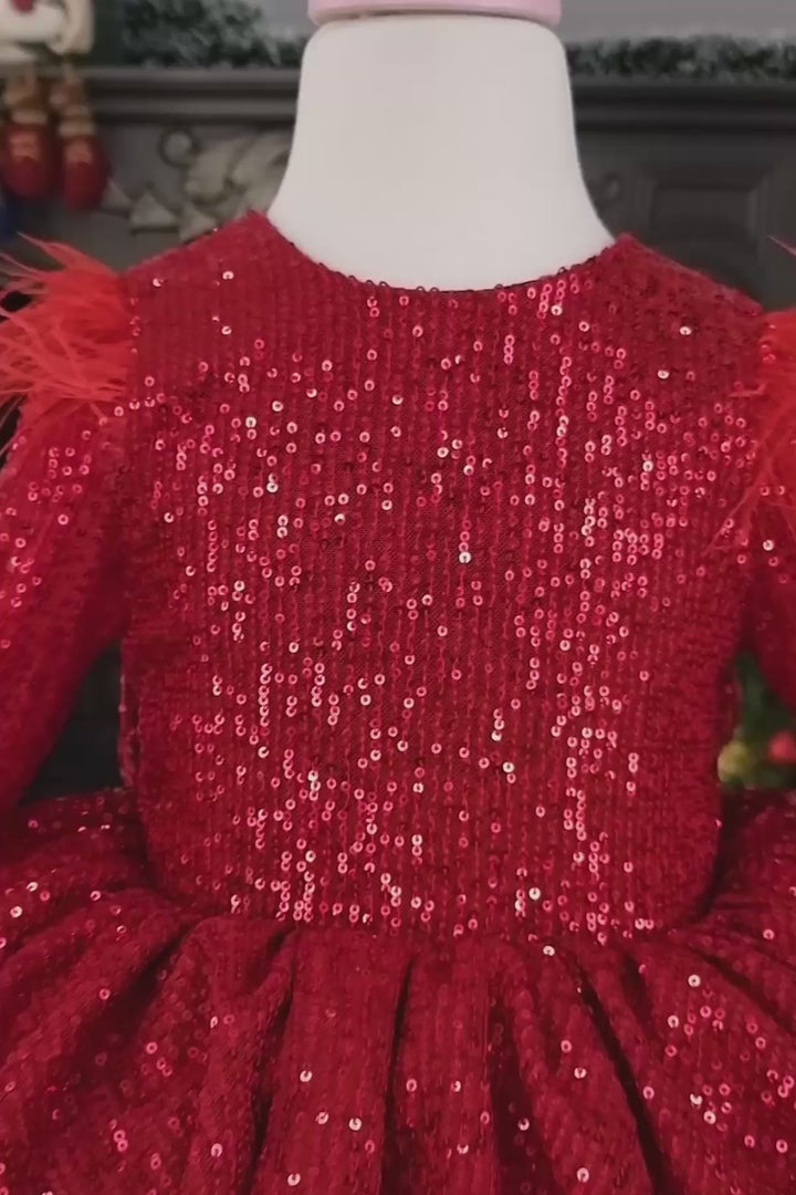 360° view of a red Christmas dress that has long sleeves, red sequin top and bow, feathers, V design, and knee length tulle layered skirt