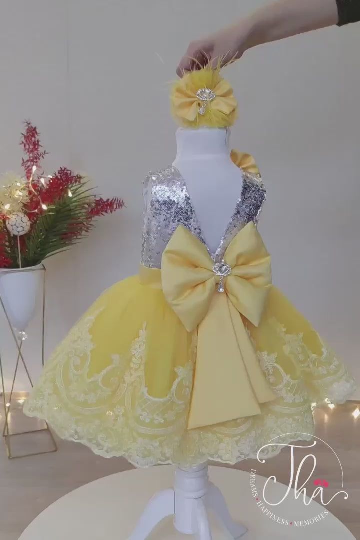 360° view of a silver and yellow party dress that has silver sequin top, knee length yellow skirt, belt and bow, and lace on hems
