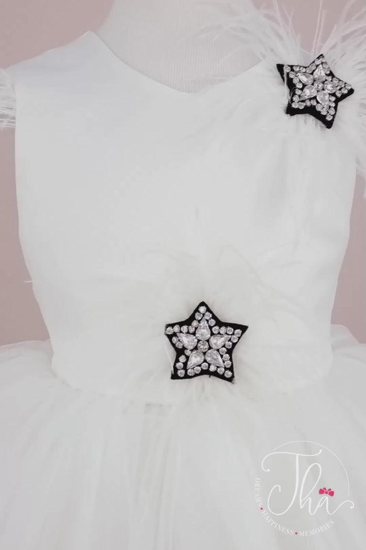 360° view of a white sleeveless fairy dress that has stars with crystal stones on top, feathers, satin top and bow, V design, and knee length skirt
