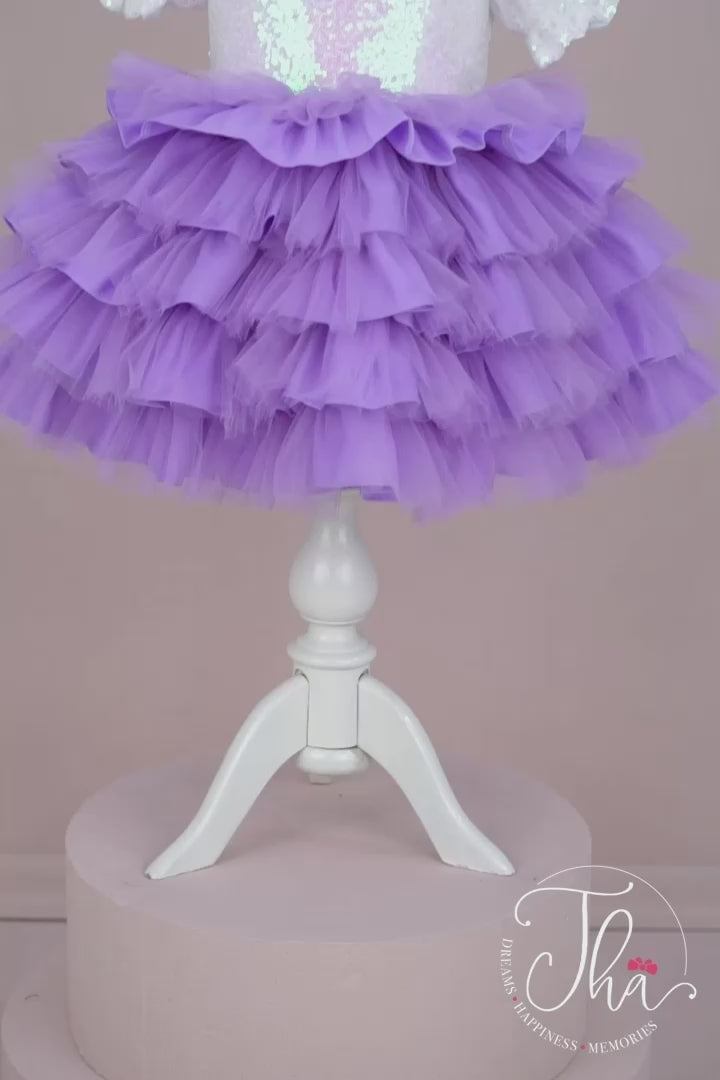 360° view of a lilac themed baby dress that has white sequin top, lilac puffy skirt, half sleeves, bow, and feathers on shoulders