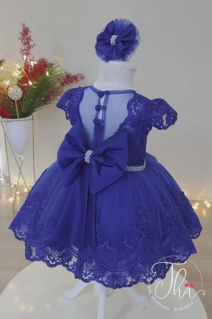 360° view of a sax blue fairy dress that has lace on top and the skirt, cap sleeves, pleat detail, bow, and pearl covered belt