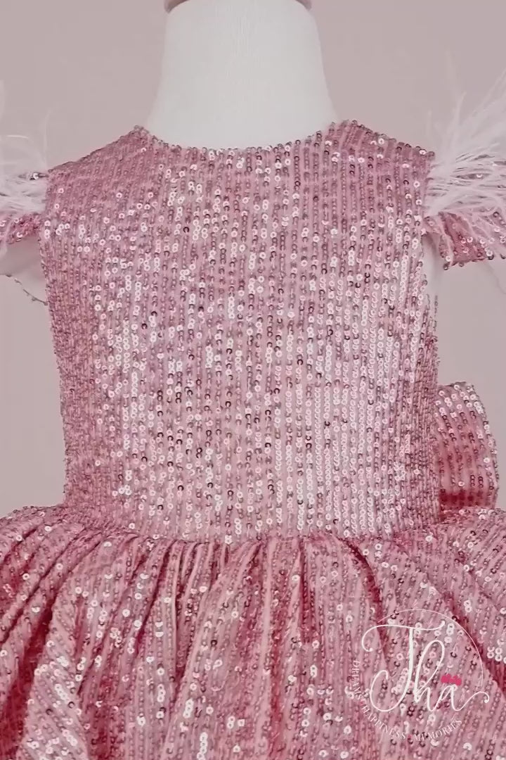 360° view of a pink fairy dress that has cap sleeves, pink sequin top and bow, feathers, V design, and knee length tulle layered skirt