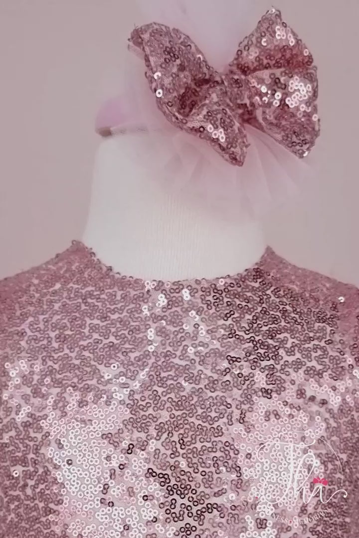 360° view of a rose gold tutu princess dress which has cap sleeve, feathers on arms, sequin fabric top, bow, and pink layered skirt