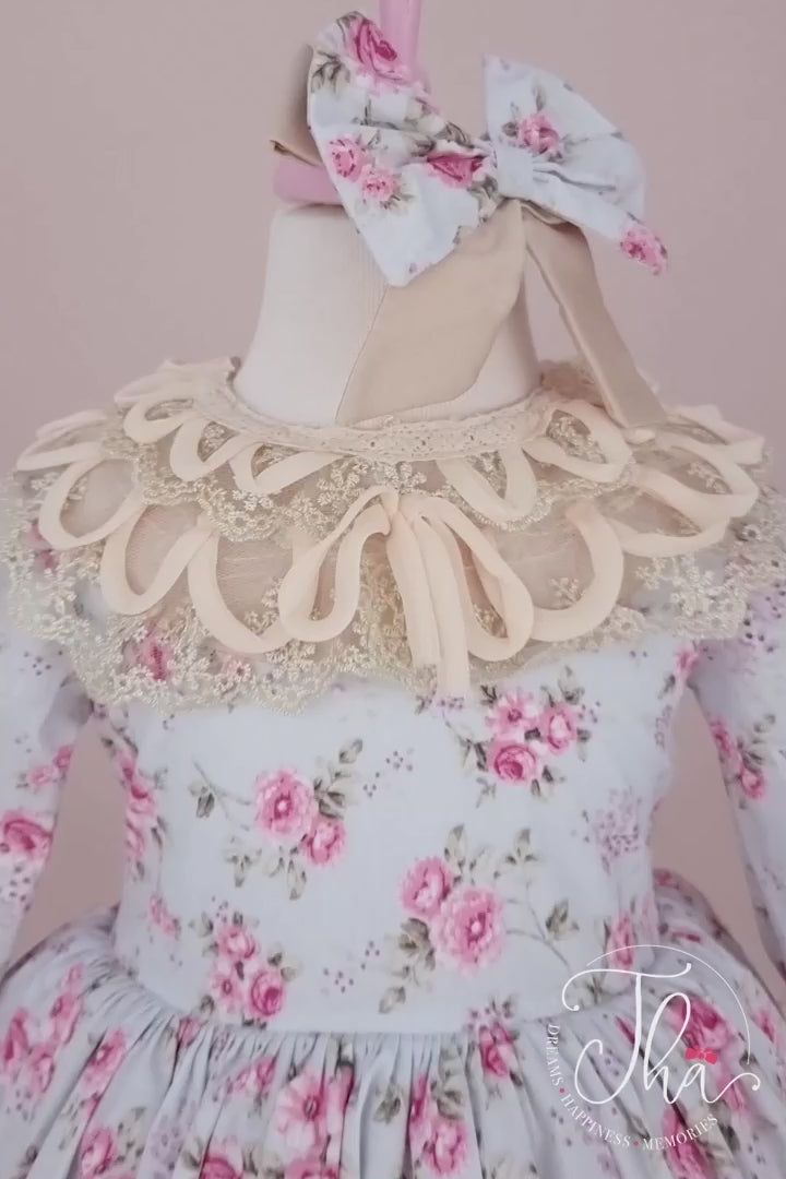 360° view of a flower printed baby dress set that has long sleeve, lace guipure sleeve ends and skirt, bow, lace on the collar, and cream shoes.