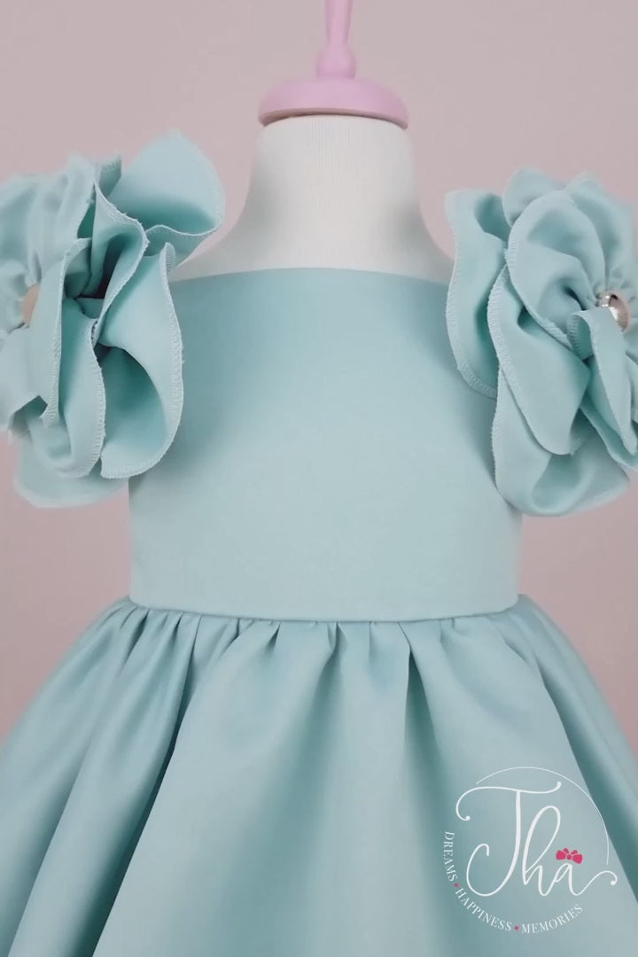 360° view of a tiffany special party concept dress that has satin fabric, 3D flowers on shoulders, boat collar, and knee length skirt