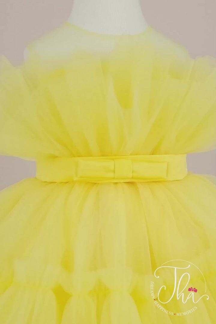 360° view of a yellow sleeveless tutu dress that has knee length fluffy multi layered skirt, belt, and yellow illusion collar