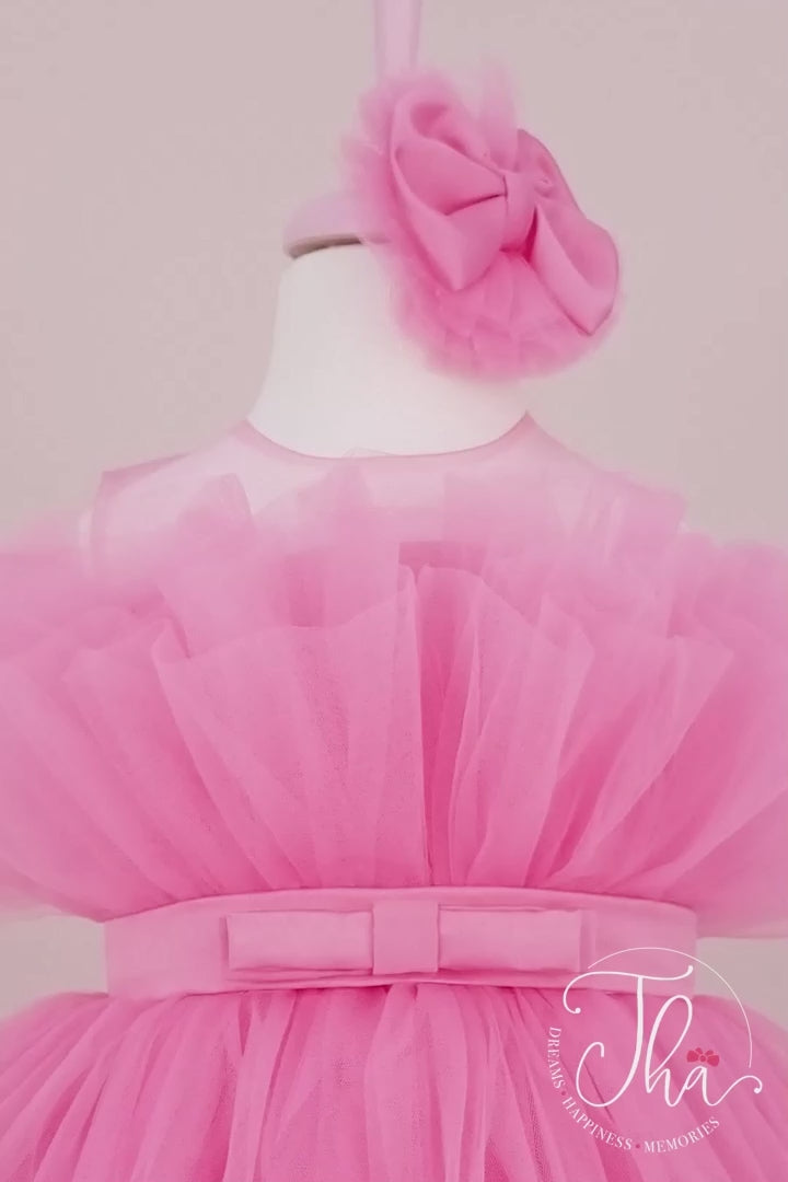 360° view of a pink sleeveless birthday dress that has knee length fluffy multi layered skirt, belt, and pink illusion collar