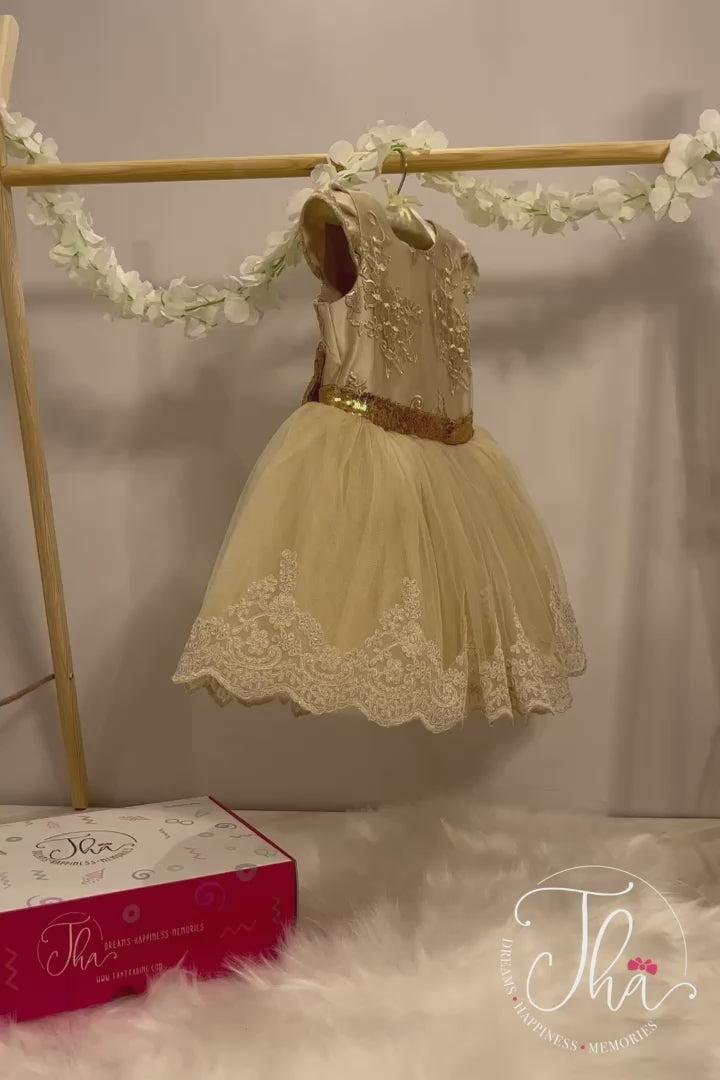 360° view of a baby birthday dress that has fluffy knee length skirt, gold belt, cap sleeves, and lace on top and bottom of the skirt