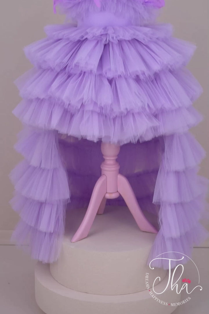 360° view of a sleeveless lilac princess wedding dress. The dress has feathers on chest, high-low layered skirt and satin top