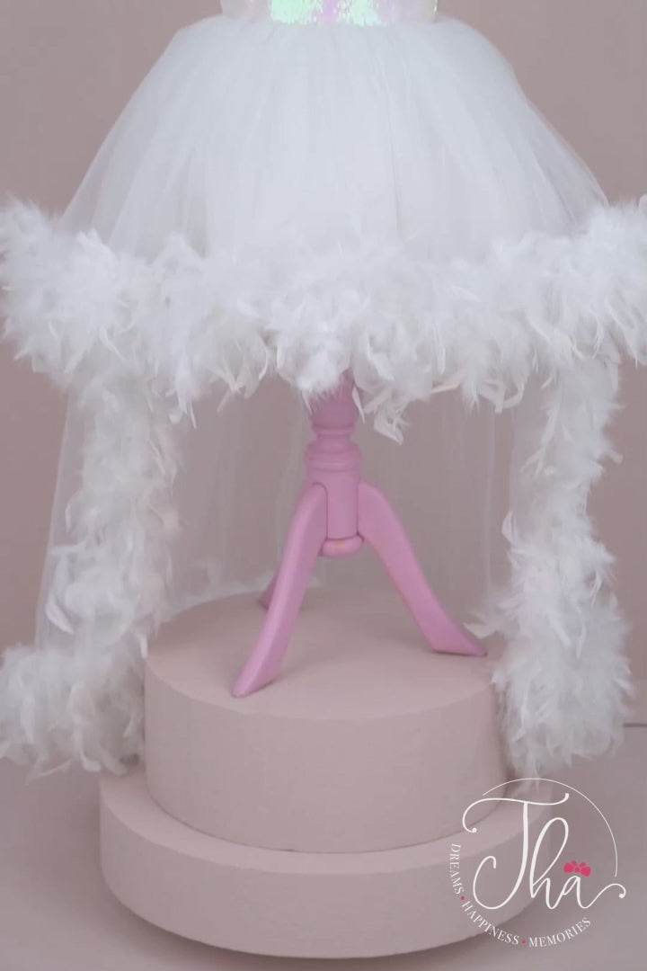 360° view of a white bridesmaid dress that has cap sleeves, feathers on shoulders and hems, hi-low skirt, V design, and white sequin top and bow