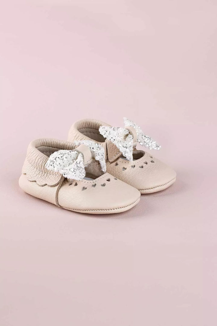 Cream baby shoes that have glitter bow tie and heart details