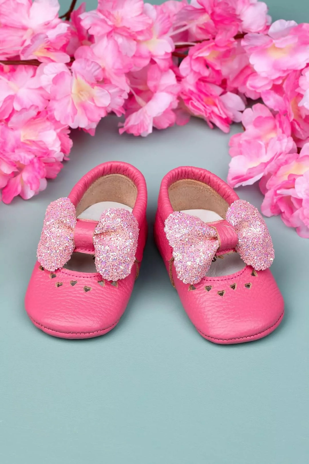 Pink baby shoes that have glitter bow tie and heart details