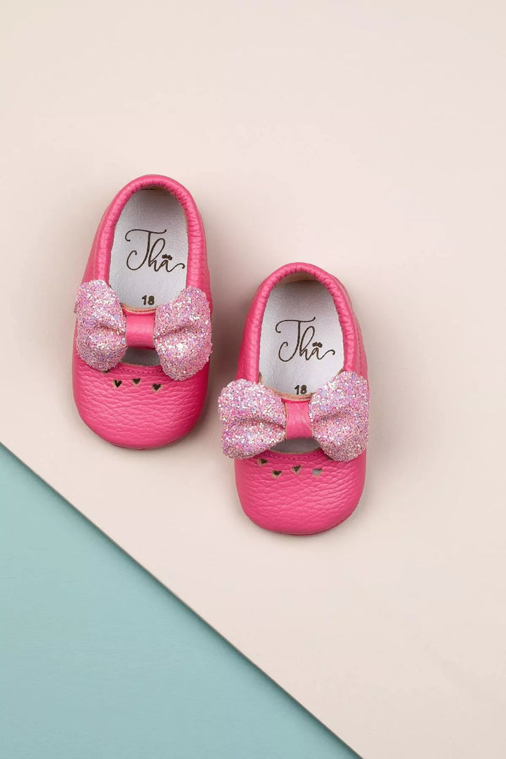 Pink baby shoes that have glitter bow tie and heart details