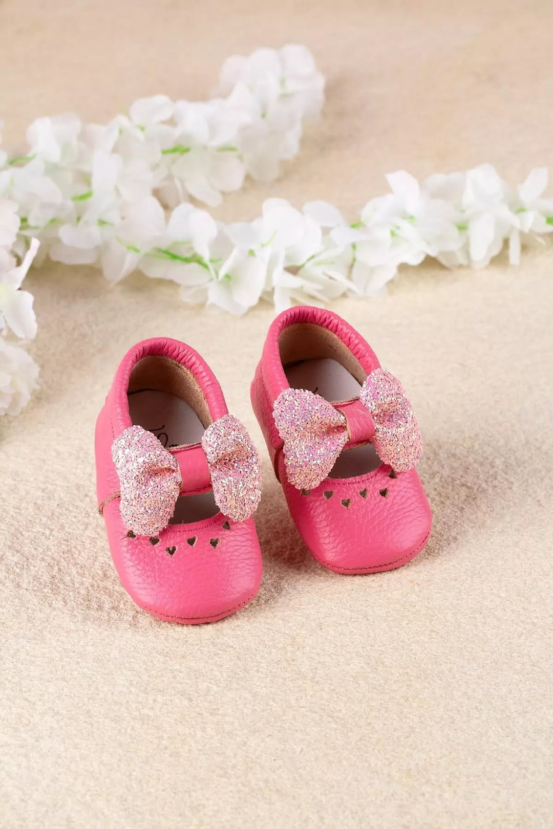 Pink baby shoes that have glitter bow tie and heart details