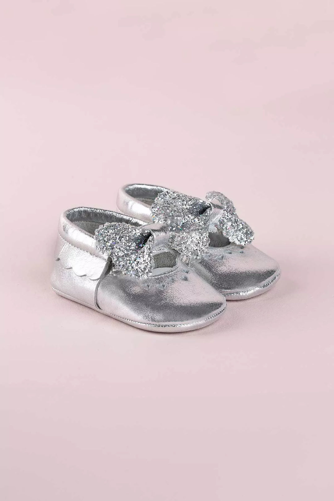 Silver baby shoes that have glitter bow tie and heart details