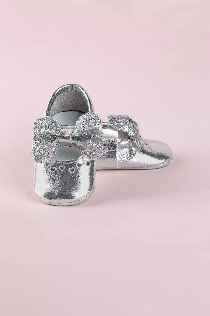 Silver baby shoes that have glitter bow tie and heart details