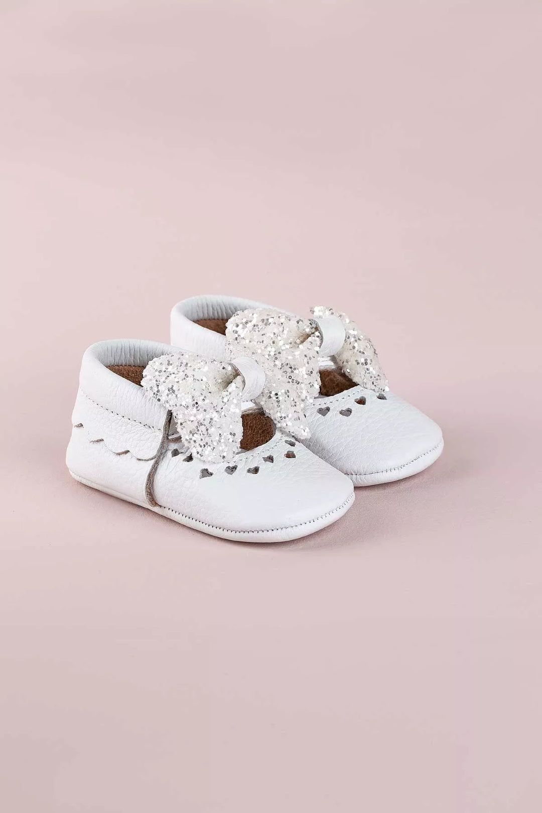 White baby shoes that have glitter bow tie and heart details