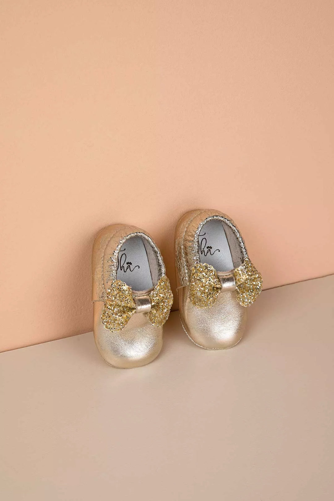 Yellow baby shoes that have glitter bow tie.
