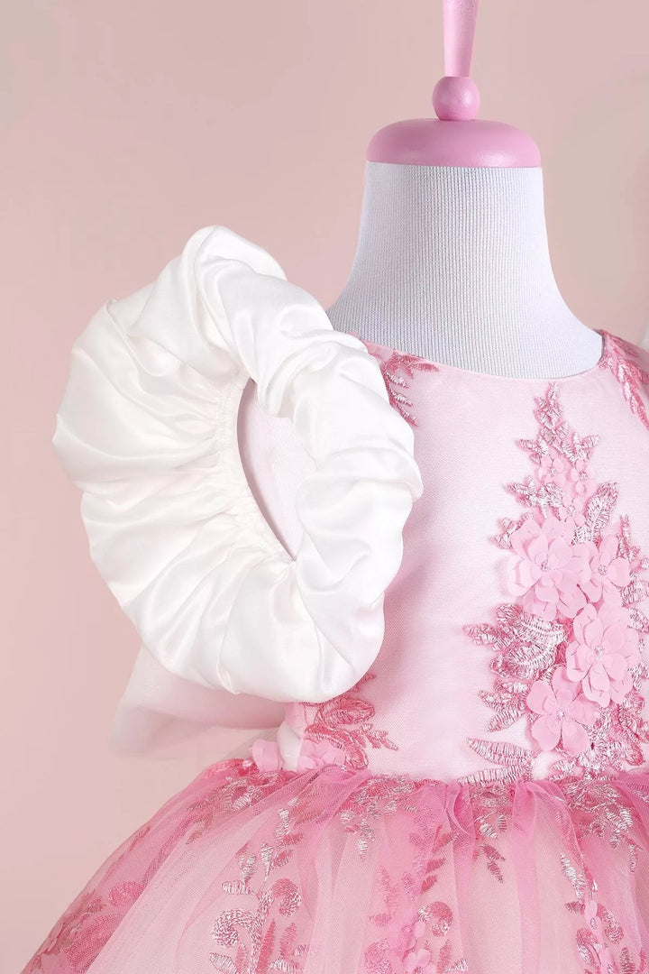 Close up view of a pink birthday party dress. The dress has 3D floral design and balloon arm