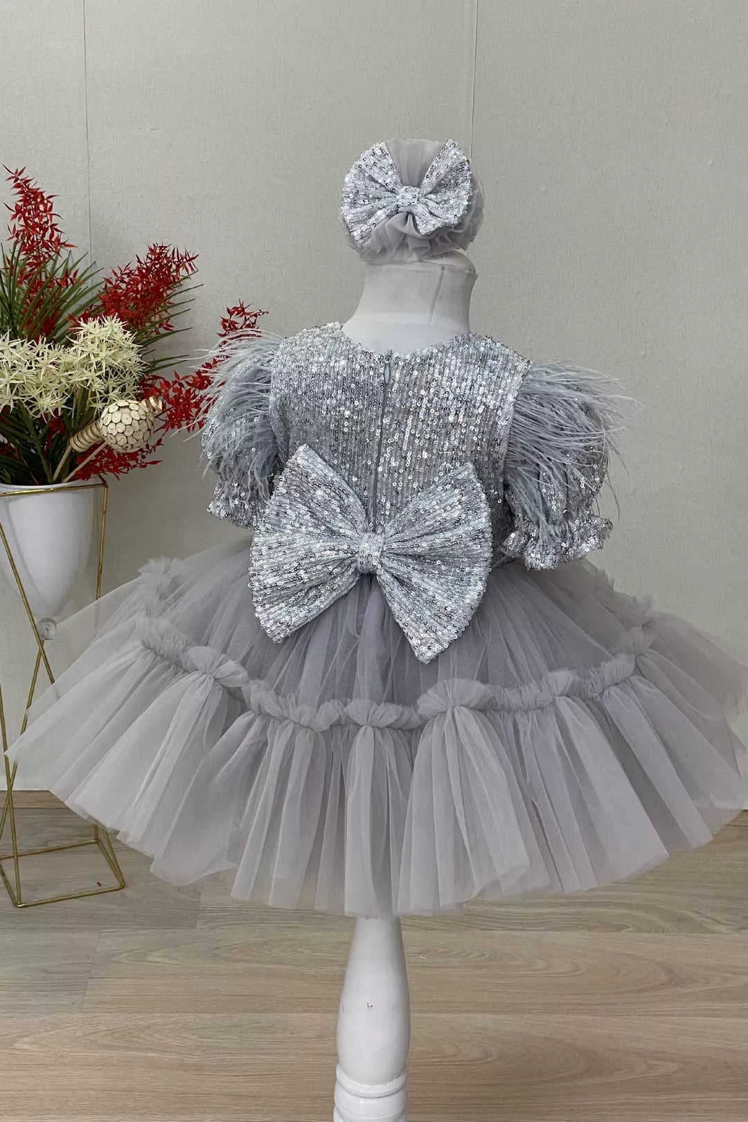 Back view of a gray girl dress that has sequins, half sleeve, feathers, V-neck, bow, and puffy skirt