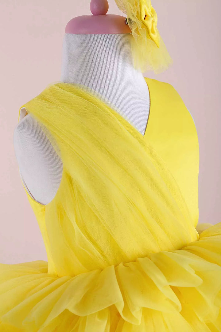 Close up view of a yellow sleeveless sun themed party dress that has knee length multi layered puffy skirt and V-neck