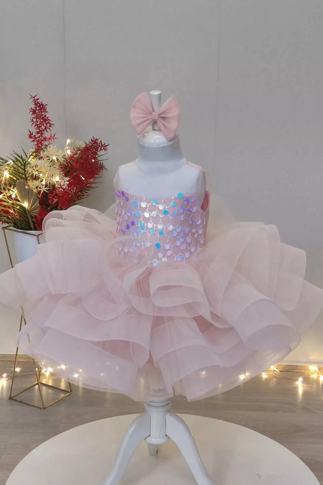 A light pink princess birthday dress that has puffy multi layered skirt, illusion collar, and hologram sequins