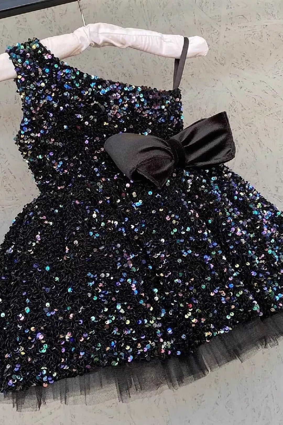 A black hologram sequin one shoulder open Christmas dress that has velvet ribbon and knee length skirt.