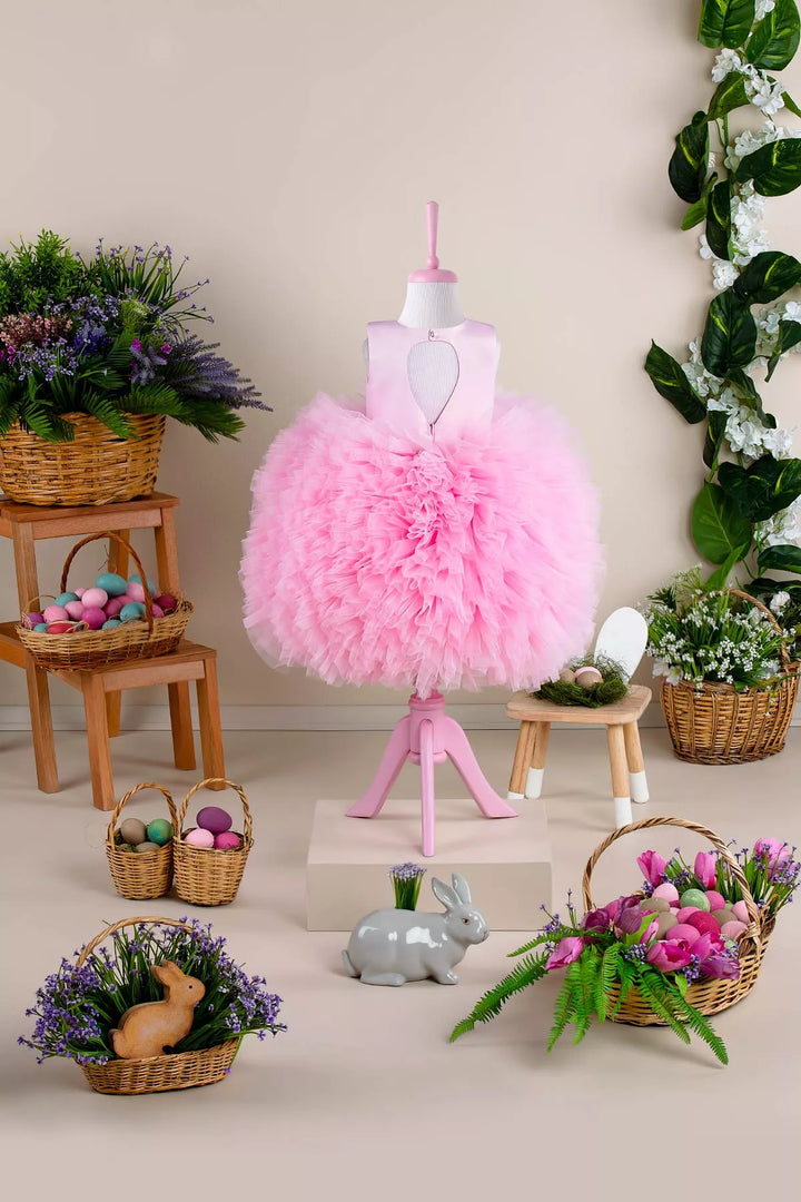 Back view of a pink sleeveless fairy dress that has see-through design, satin top, and knee length asymmetrical puffy skirt with Easter decorations