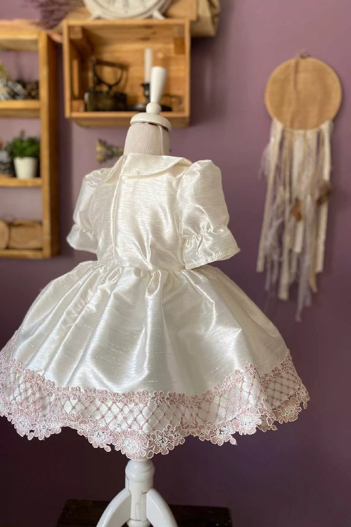 Back view of a white vintage dress that has baby collar, shirred half sleeves, French lace on hems, and knee length skirt