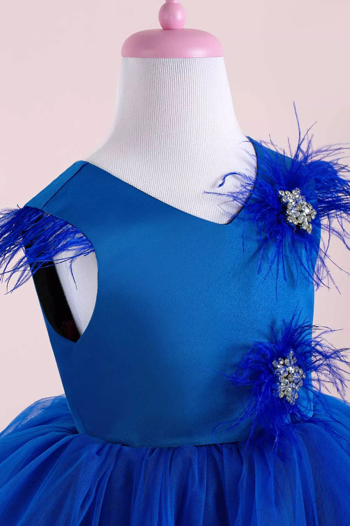 Close up view of a sax blue sleeveless stage dress that has stars with crystal stones on top, feathers, satin top, and tulle and satin knee length skirt