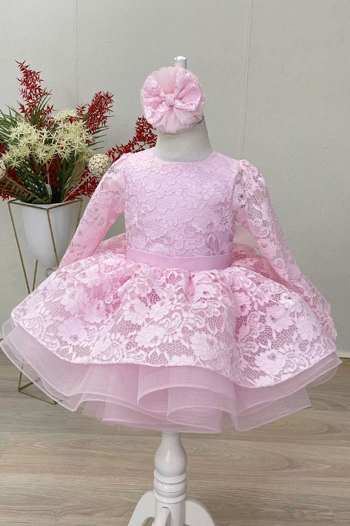 A pink candy girl dress that has long lace sleeves, floral lace, satin belt, and grain tulle knee length skirt