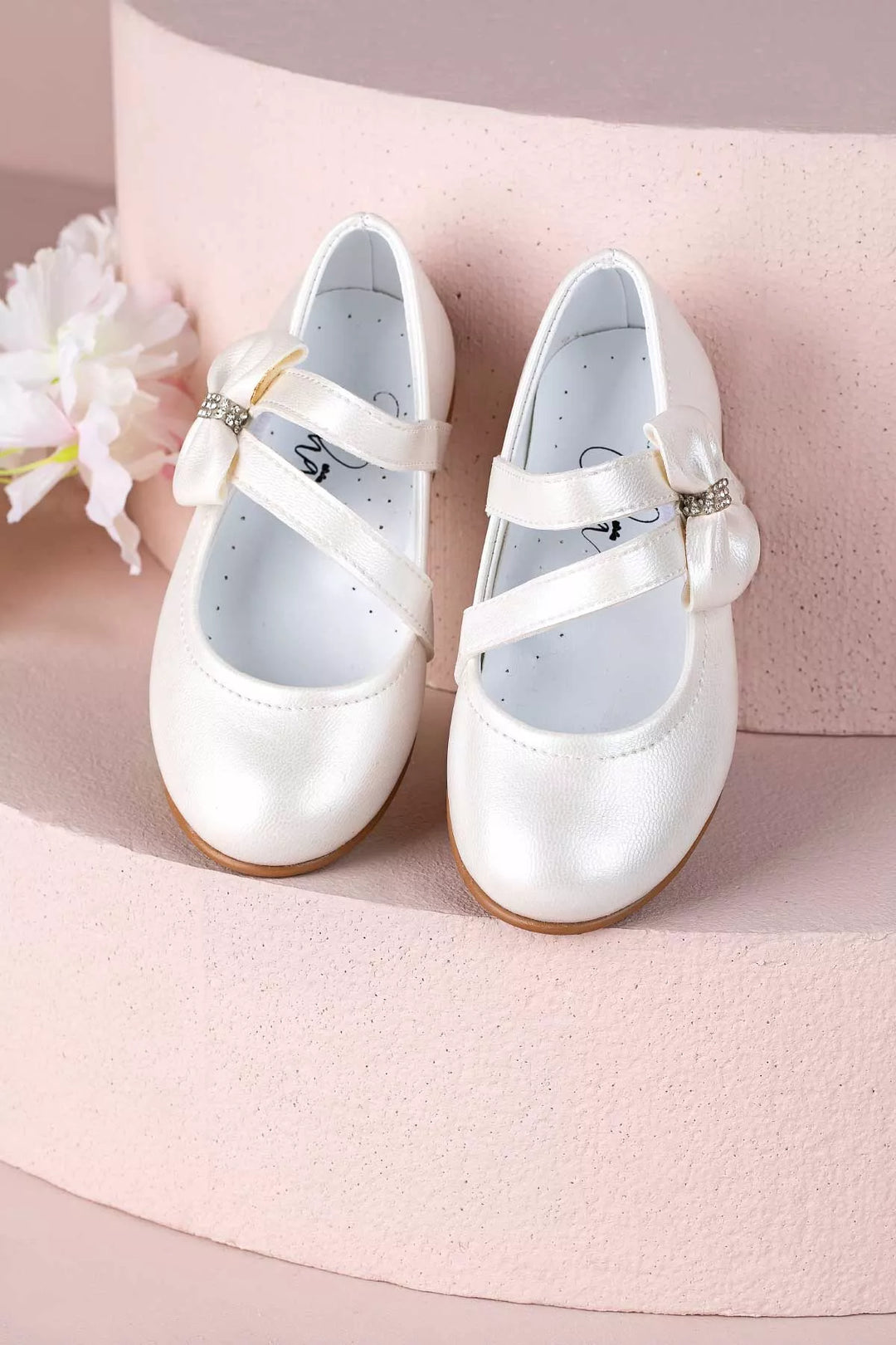 Ivory toddler shoes that have crystal stone ornaments and bow tie
