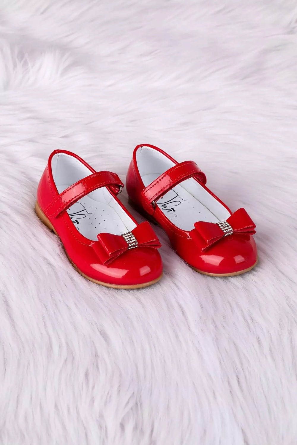 Red toddler shoes that have crystal stone ornaments and bow tie