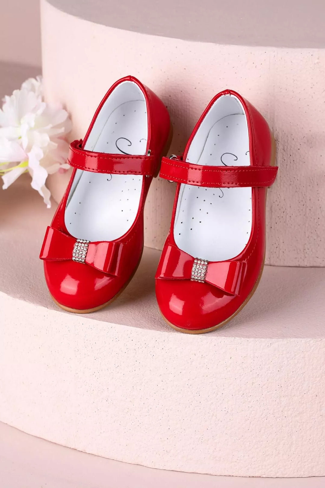 Red toddler shoes that have crystal stone ornaments and bow tie