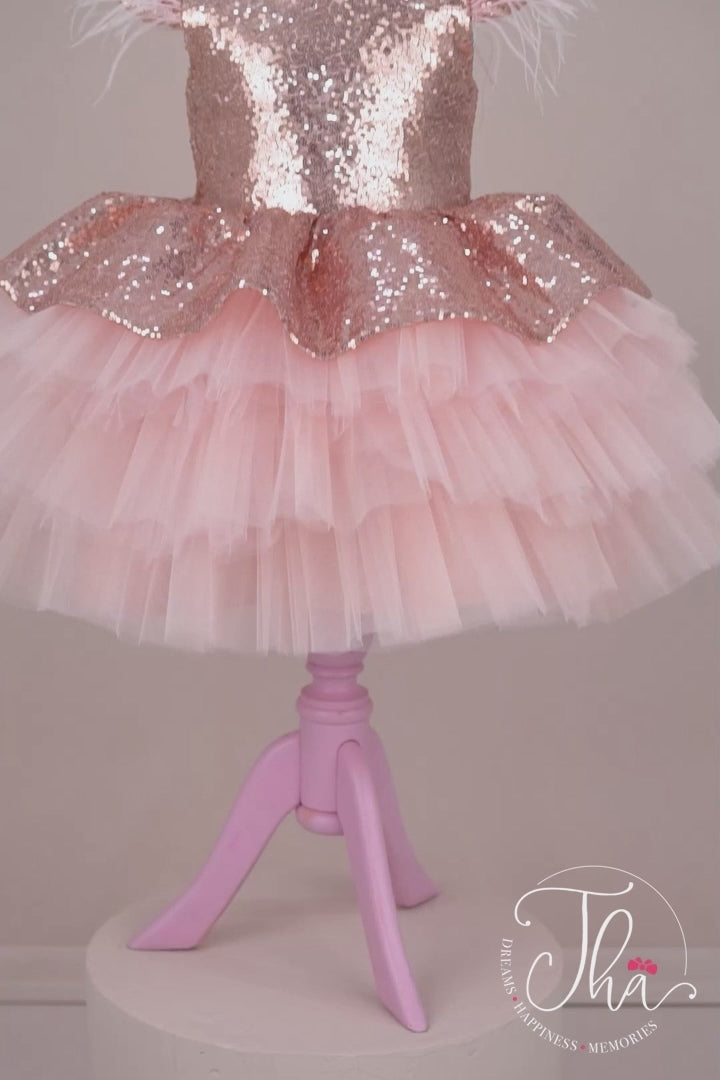 360° view of a salmon tutu princess dress which has cap sleeve, feathers on arms, sequin fabric top, bow, and layered skirt