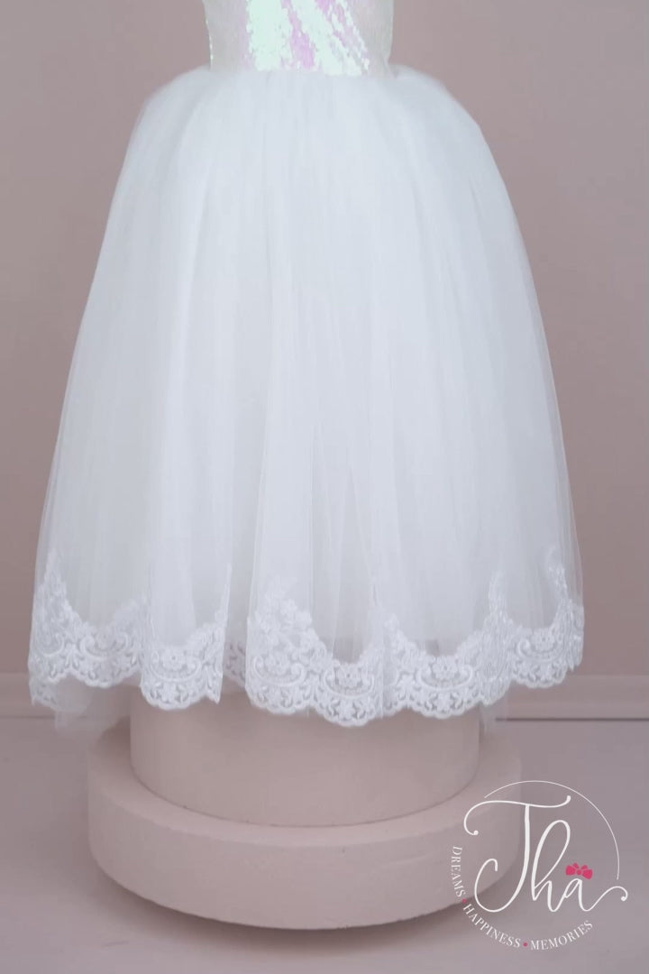 360° view of a white floor length flower girl dress that has white sequin top, one shoulder design and French lace on hems